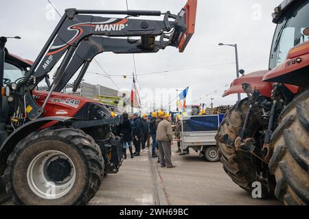 Strasburgo, Francia - 6 febbraio 2024: Gruppo di agricoltori adulti e anziani con trattori bloccano l'ingresso del Parlamento europeo, protestando contro i prodotti alimentari importati con standard più bassi e nuovi OGM. Foto Stock