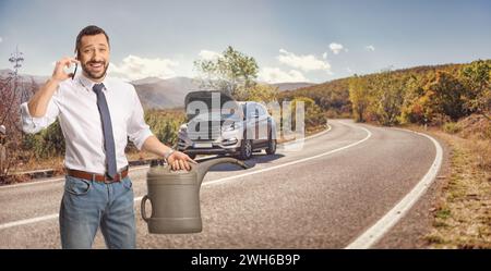 Uomo con un problema alla macchina che tiene in mano una tanica di benzina e utilizza uno smartphone mentre è in viaggio Foto Stock