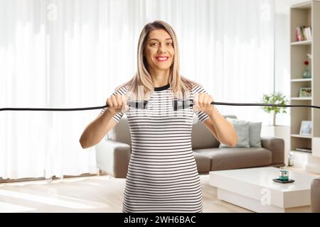 Una giovane donna che collega i cavi in salotto e sorride alla fotocamera Foto Stock
