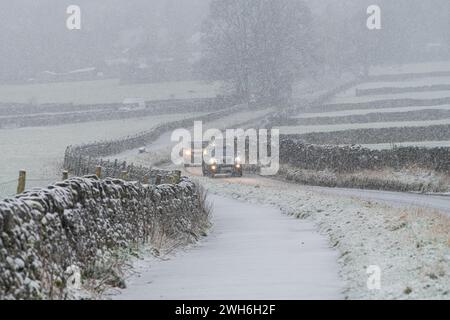 Hope Valley, Peak District, Derbyshire, 8 febbraio 2024. I veicoli si fanno strada attraverso la neve pesante questa mattina su Arthurs Way nella Hope Valley. Crediti: Michael Jamison/Alamy Live News Foto Stock