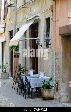Due piccoli tavoli da ristorante disposti per cenare all'aperto in una strada di Riva del Garda, Italia Foto Stock