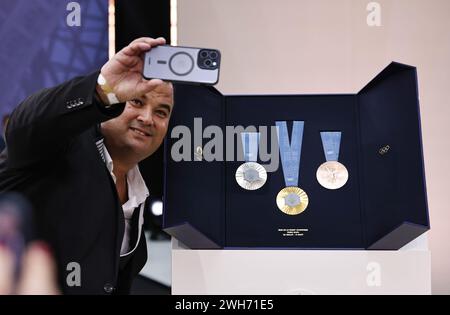 Saint Denis. 8 febbraio 2024. Un uomo scatta un selfie con le medaglie olimpiche di Parigi 2024 durante la cerimonia rivelatrice agli organizzatori olimpici di Parigi a Saint-Denis, vicino Parigi, Francia, 8 febbraio 2024. Le medaglie assegnate alle Olimpiadi e alle Paralimpiadi di Parigi di quest'anno saranno caratterizzate da un pezzo di ferro a forma esagonale prelevato dalla Torre Eiffel al centro, come hanno detto gli organizzatori mentre hanno svelato il loro disegno giovedì. Crediti: Gao Jing/Xinhua/Alamy Live News Foto Stock