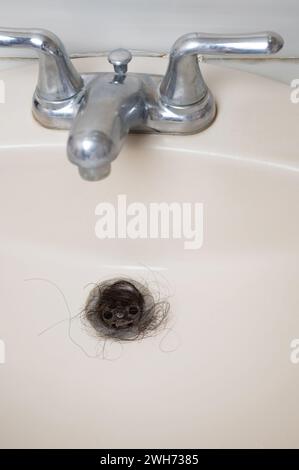 Foro di scarico ostruito nel lavandino con capelli scuri vista ravvicinata Foto Stock