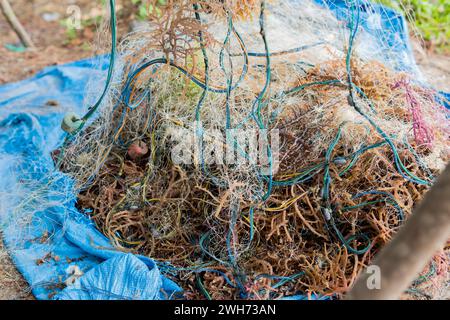 Mucchi di reti da pesca e alghe marine sul molo del porto Foto Stock