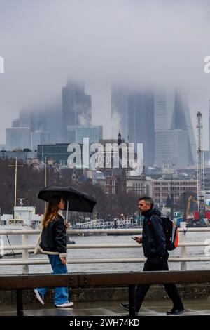 Londra, Regno Unito. 8 febbraio 2024. La città è avvolta da nuvole di tempesta e nebbia, mentre i pendolari e i visitatori camminano attraverso il Waterloo Bridge, la maggior parte porta ombrelli contro la pioggia costante - il clima umido e freddo dell'ultimo sistema di tempeste arriva a Londra. Crediti: Guy Bell/Alamy Live News Foto Stock