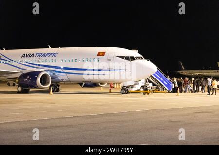 Bishkek, Kirghizistan - 26 settembre 2023: Persone che camminano su scale aeree fino all'aereo Avia Traffic all'aeroporto internazionale di Manas di notte Foto Stock