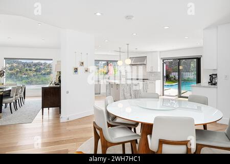 Una moderna area da pranzo con un elegante tavolo bianco circondato da eleganti sedie grigie, adiacente ad una Foto Stock