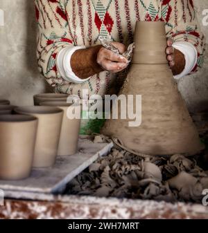 vasaio marocchino che lancia a mano un gruppo di tazze di argilla su una ruota per la vendita sul mercato Foto Stock