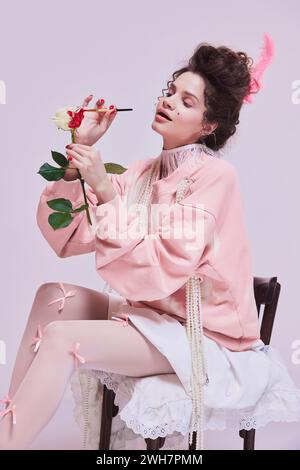 Bella giovane donna che dipinge il fiore di rosa bianco con il colore rosso. Rendere la vita più luminosa, dare più passione. Foto Stock