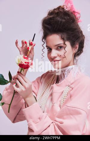 Bella giovane donna che dipinge il fiore di rosa bianco con il colore rosso. Rendere la vita più luminosa, dare più passione. Foto Stock