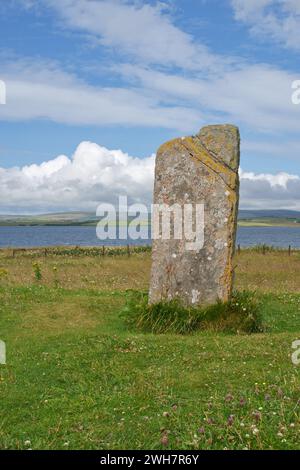 Una pietra storica sull'isola delle Orcadi con il mare e le colline sullo sfondo Foto Stock