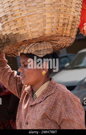 Donna che porta un cesto in testa, Goa India. Donna indiana con un grande cesto in testa. In India, questo è un modo popolare per portare cose pesanti. Strada Foto Stock