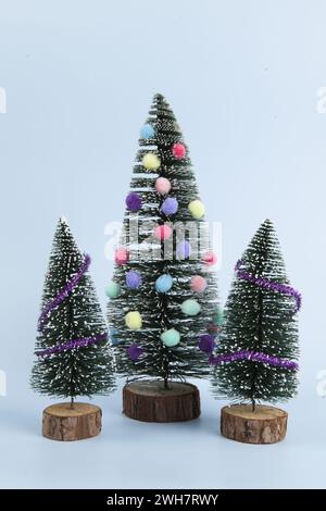albero di natale in miniatura decorato con mini ghirlande e pompon come baubles. Sfondo blu. Fotografia di natura morta minima Foto Stock
