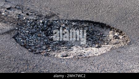 Grande fossa sulla strada. Concetto di riparazione della pavimentazione e sostituzione dell'asfalto. Foto Stock