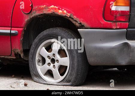 Il retro di una vecchia auto arrugginita con una ruota perforata. Riciclare vecchie auto. Foto Stock