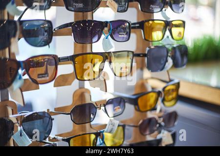 Portatelo in un negozio con molti occhiali da sole nei colori grigio scuro e giallo per la guida. Negozio di ottica, cura degli occhi. Bishkek, Kirghizistan - 26 maggio 2023. Foto Stock
