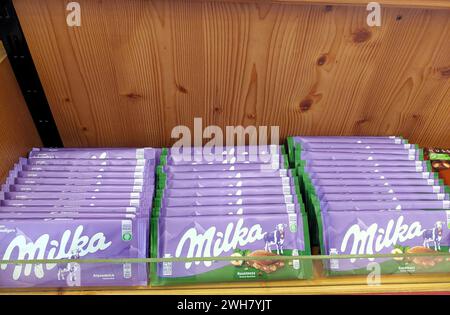 Una gamma di barrette di cioccolato Milka organizzate ordinatamente sugli scaffali di un supermercato, che mostrano il famoso marchio di dolciumi. Foto Stock