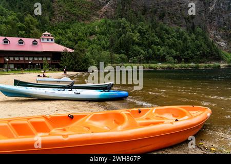 Three Valley Gap British Columbia Canada, 12 gennaio 2023: Kayak e canoa parcheggiati su una spiaggia sabbiosa che si affaccia su un castello di montagna sul lago e sul Foto Stock