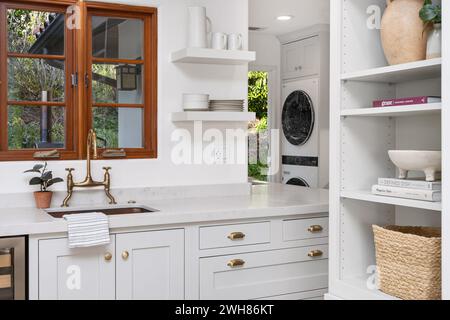 Una cucina compatta con armadi bianchi e ripiani aperti Foto Stock