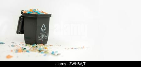 Foto macro di un mini contenitore di plastica pieno di microplastica. Concetto di inquinamento idrico e riscaldamento globale. Scatto macro con bassa profondità di campo o. Foto Stock