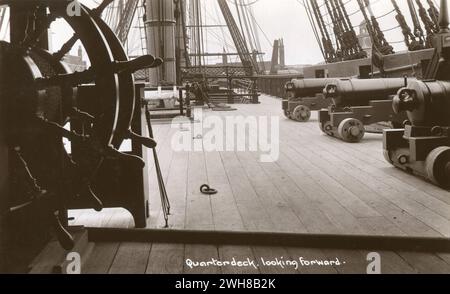 Portsmouth. Circa 1930 anni Una vera cartolina fotografica d'epoca intitolata "Quarterdeck, Looking At", raffigurante il quarterdeck della HMS Victory, una nave di prima classe da 104 cannoni di linea della Royal Navy. La nave è nota soprattutto per il suo ruolo di Horatio, ammiraglia di Lord Nelson nella battaglia di Trafalgar il 21 ottobre 1805. Situata nel bacino di carenaggio di Portsmouth Historic Dockyard, Hampshire, è la nave navale più antica del mondo ancora in servizio. Foto Stock