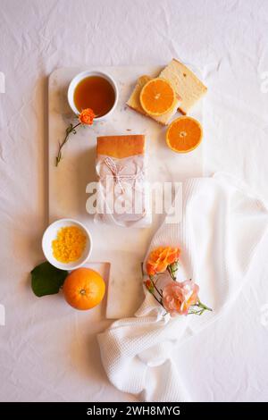 Torta madeira all'arancia servita con sciroppo e scorza d'arancia. Piano con tavolo da tè pomeridiano. Foto Stock