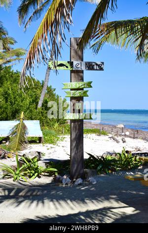 Un cartello sulla spiaggia che recita Ël Norte, bere, mangiare e ripetere su una spiaggia a nord di Ambergris Caye, Belize, America centrale. Foto Stock