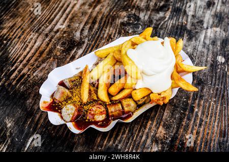 Delizioso Duo tedesco: Currywurst & patatine fritte con Mayo Dieses köstliche foto vom 02. February 2024 fängt die klassische deutsche Streetfood-Kombination ein: eine saftige Currywurst in einem reichhaltigen, würzigen Curryketchup, begleitet von goldenen, knusprigen Pommes frites und einem großzügigen Klecks cremiger mayonnaise. DAS kräftige Rot der Currysauce bildet einen schönen Kontrast zu den goldbraunen Pommes frites und der Weißen mayonnaise, wodurch ein optisch ansprechendes und appetitliches Bild entsteht. Dieses Gericht verkörpert die Gemütlichkeit und Vertrautheit der deutschen Küche und eign Foto Stock