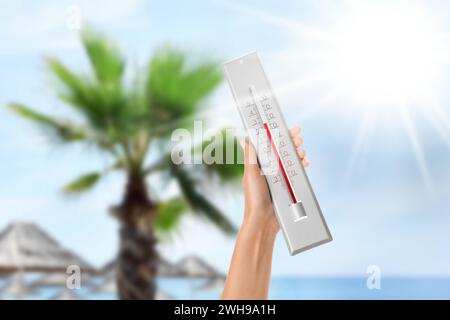 Donna che tiene il termometro sulla spiaggia in estate, primo piano Foto Stock