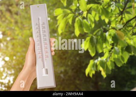 Donna che tiene il termometro all'aperto in primavera, primo piano Foto Stock