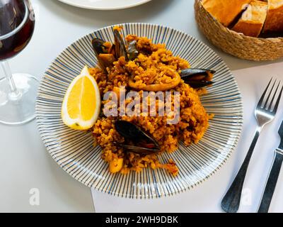 Paella di frutti di mare con cozze, anelli di calamari e limone Foto Stock