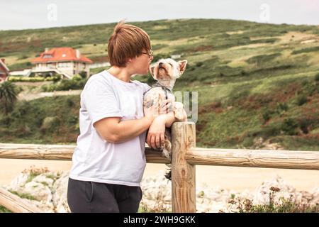 Santander, Spagna. 7 luglio 2023 donna sorridente felice che tiene in braccio il cane terrier dello Yorkshire. Persone con animali domestici canini, adorabili cuccioli all'aperto. Foto verticale Foto Stock