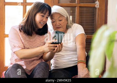 La figlia giapponese adulta condivide le foto scattate con il suo smartphone con la sua anziana madre. Foto Stock