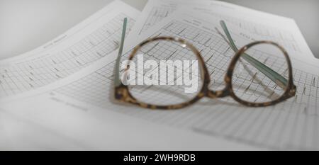 Referti ECG ECG ECG stampati su fogli. Un paio di occhiali da lettura Foto Stock