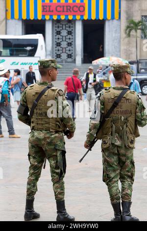 MEDELLIN, COLOMBIA - 14 MARZO: Due militari in piedi sulla piazza con l'arma automatica in mano e persone intorno. Le ultime mostre di El Circo Botero Foto Stock