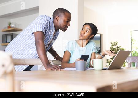 Un giovane afroamericano e una donna birazziale, che sono una coppia, esaminano le loro finanze a casa Foto Stock