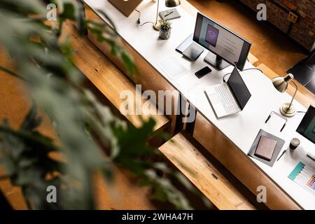 Un moderno e informale ufficio d'affari dispone di una scrivania pulita con gadget tecnologici Foto Stock