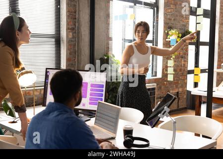 Una donna asiatica conduce una riunione di lavoro informale in un ufficio moderno Foto Stock