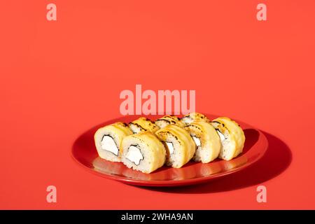 Sushi Philadelphia su un piatto rosso isolato su sfondo rosso scuro. Concetto creativo di cibo Foto Stock