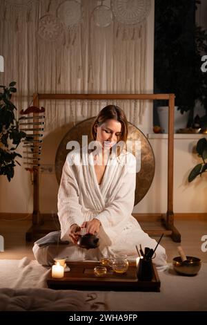 La giovane donna sta versando tè caldo durante una cerimonia del tè. Foto Stock