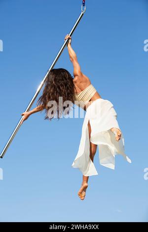 Aerialist professionista che si esibisce su un palo da ballo aereo all'aperto Foto Stock