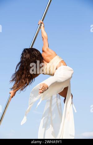 Aerialist professionista che si esibisce su un palo da ballo aereo all'aperto Foto Stock