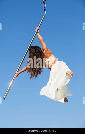 Aerialist professionista che si esibisce su un palo da ballo aereo all'aperto Foto Stock