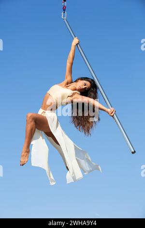 Aerialist professionista che si esibisce su un palo da ballo aereo all'aperto Foto Stock