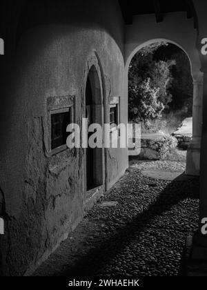 Cherso, Croazia - 24 ottobre 2022: Stretta via di Cherso di notte, ingresso a una cappella, bianco e nero Foto Stock