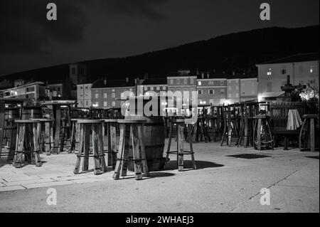 Cres, Croazia - 24 ottobre 2022: Il porto di Cres nella notte, sedie vuote di un bar, bianco e nero Foto Stock