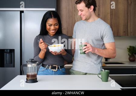 Coppia multietnica che si diverte mentre si fa colazione in cucina. Foto Stock