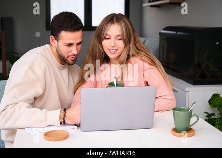 Coppia spagnola che usa il portatile insieme mentre beve un caffè. Foto Stock