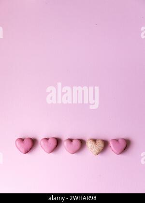 Cinque macaron rosa a forma di cuore su sfondo rosa brillante Foto Stock