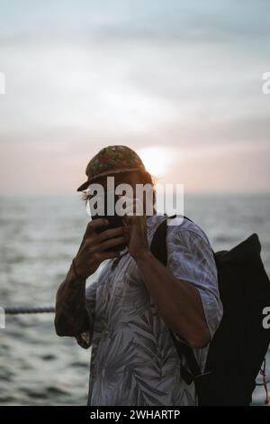Uomo viaggiatore con zaino in posto turistico scatta foto al telefono. Foto Stock